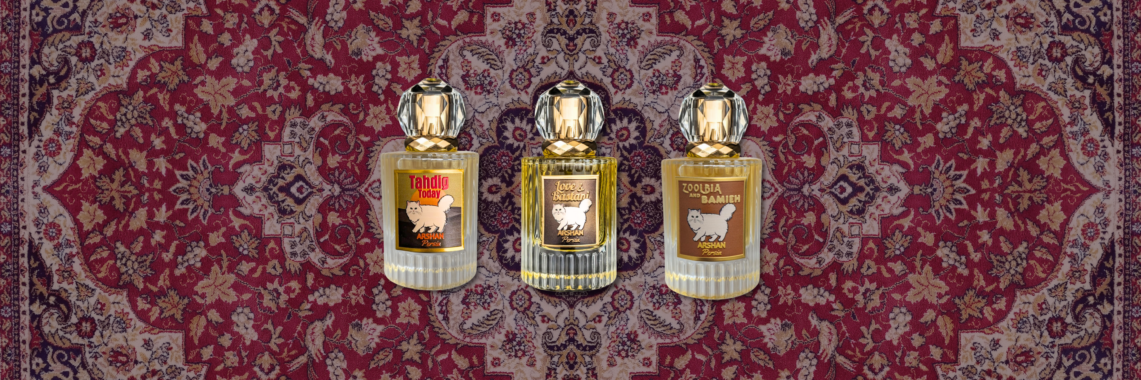 Three clear ribbed glass perfume bottles with large, faceted clear crystal caps and gold necks, arranged horizontally against the background of an intricate red, cream, and purp Persian rug pattern. Each bottle features a label with a gold border and an illustration of a fluffy white Persian cat. From left to right, the labels read: 'Tahdig Today', 'Love & Bastani', and 'Zoolbia and Bamieh' All labels feature the sub-text 'Arshan Persia' below the Persian cat.