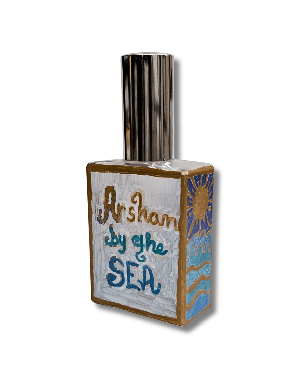 An original hand-painted decorative rectangular bottle with a metallic silver cap, featuring hand-painted artwork on the front and side. The front is painted white with the words 'Arshan by the SEA' in blue and gold lettering, and the side depicts a blue sun and waves with gold accents.